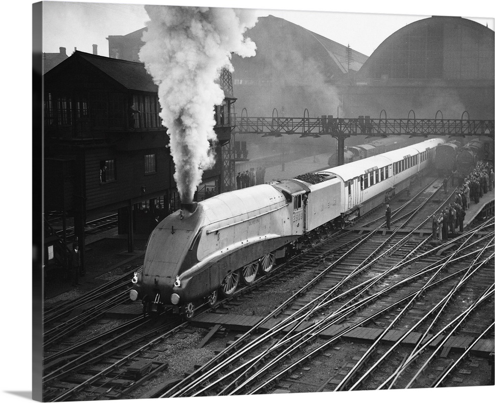 The gleaming Silver Link emits a jet of steam as it passes a platform crowded with onlookers.