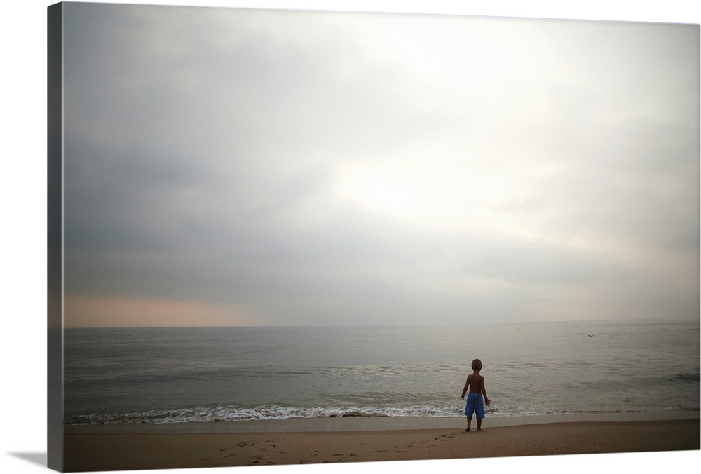 Small boy looking at sky and ocean