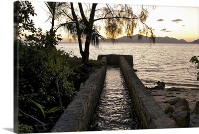 Small canal flowing into the sea at sunset