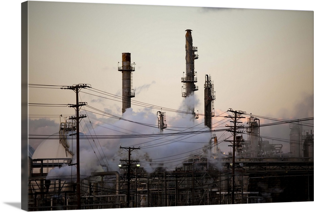 Smoke stacks and distillation towers rise out of a thicket of power lines and plumes of steam at an oil refinery complex j...
