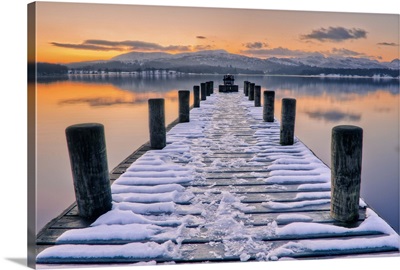 Snow covered jetty leading to beautiful sunset scene.
