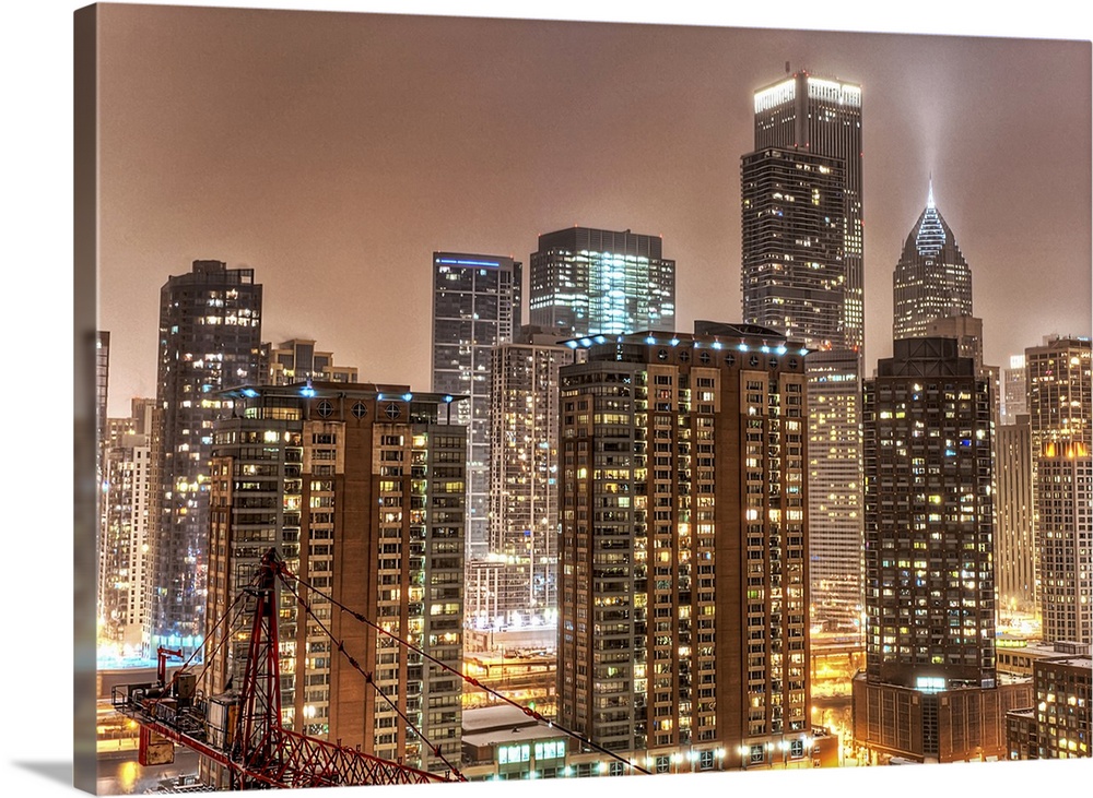 A photograph taken of the Chicago skyline at night with the buildings illuminated and snow beginning to fall on the city.