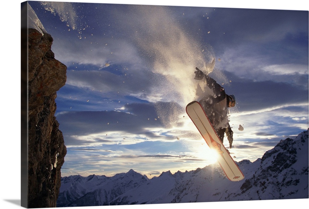 MALE SNOWBOARDER JUMPING OFF ROCK