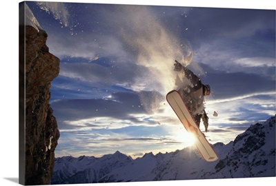 Snowboarder jumping off rock