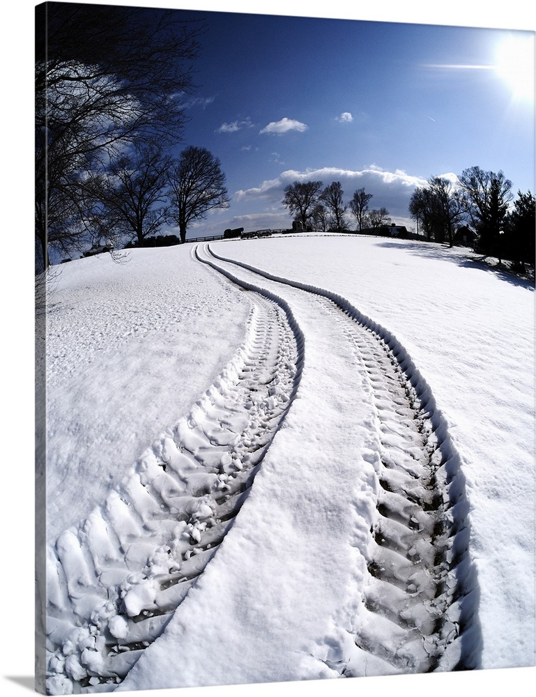 Snow covered field in Virginia with four-wheel drive truck tracks leading across it.