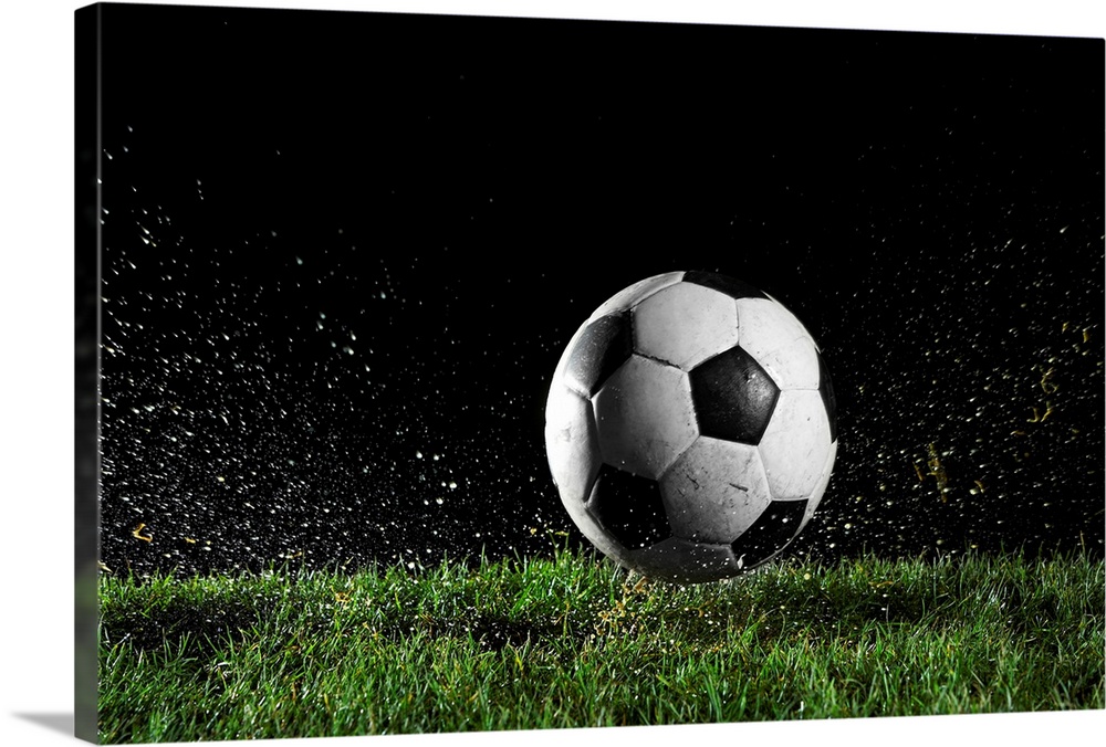 Photographic print of a soccer ball moving across wet grass from a kick.