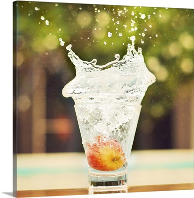 Splash in glass of water with tiny apple