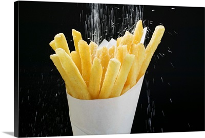 Sprinkling salt on fries in paper cone