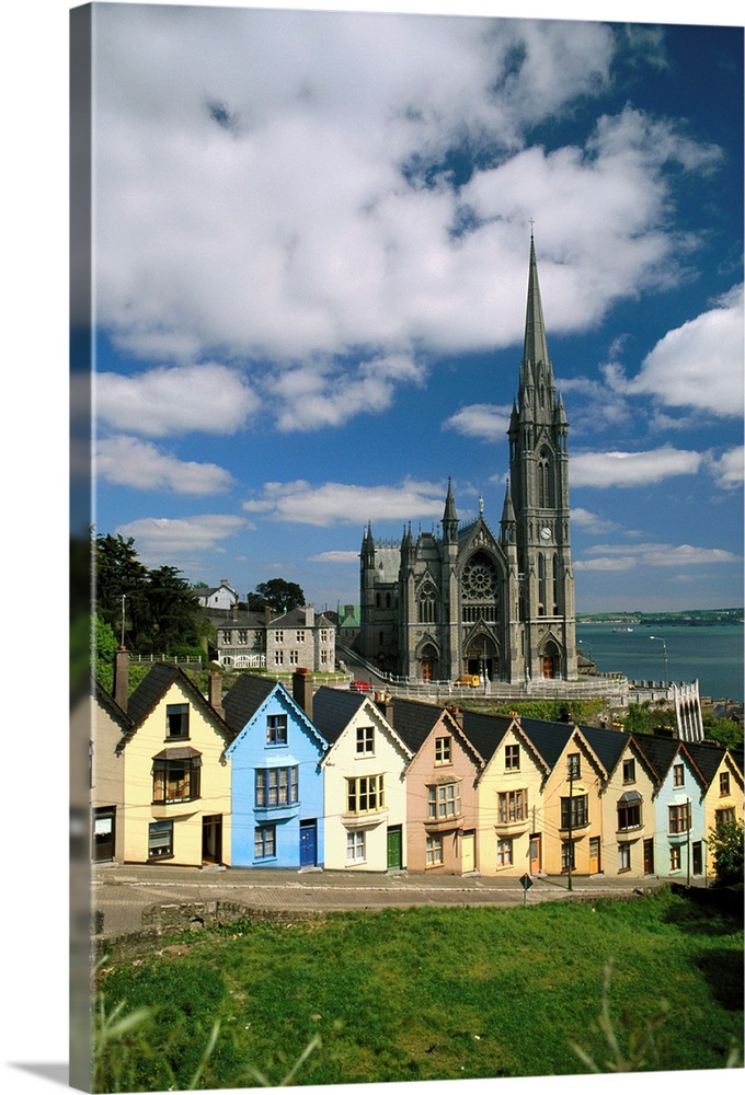 St. Coleman's Cathedral towers over multicolored row houses in the town of Cobh, in Cork County, Ireland. Cork Harbor is v...