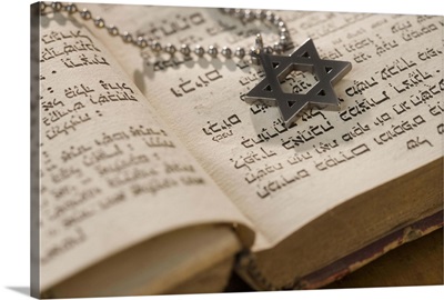 Star of David necklace on book with Hebrew text