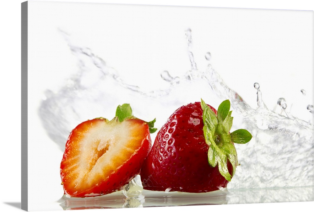 Horizontal, photograph on large canvas of two strawberries, one cut in half, with water splashing them from behind. On a s...
