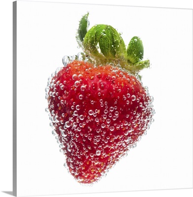 Strawberry fruit submerged in water and covered in bubbles