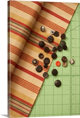 Striped textile, buttons, and tailor's instrument of measurement, overhead view