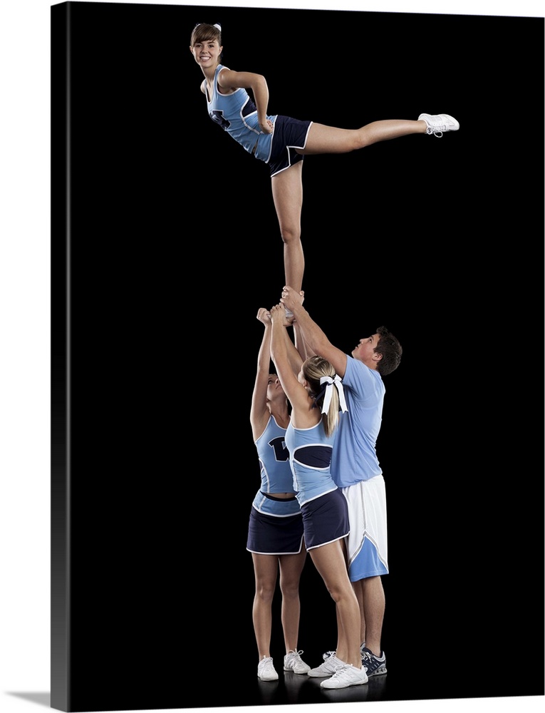 Studio shot of cheerleaders (16-17) supporting friend standing on one leg