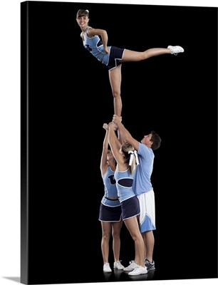 Studio shot of cheerleaders  supporting friend standing on one leg