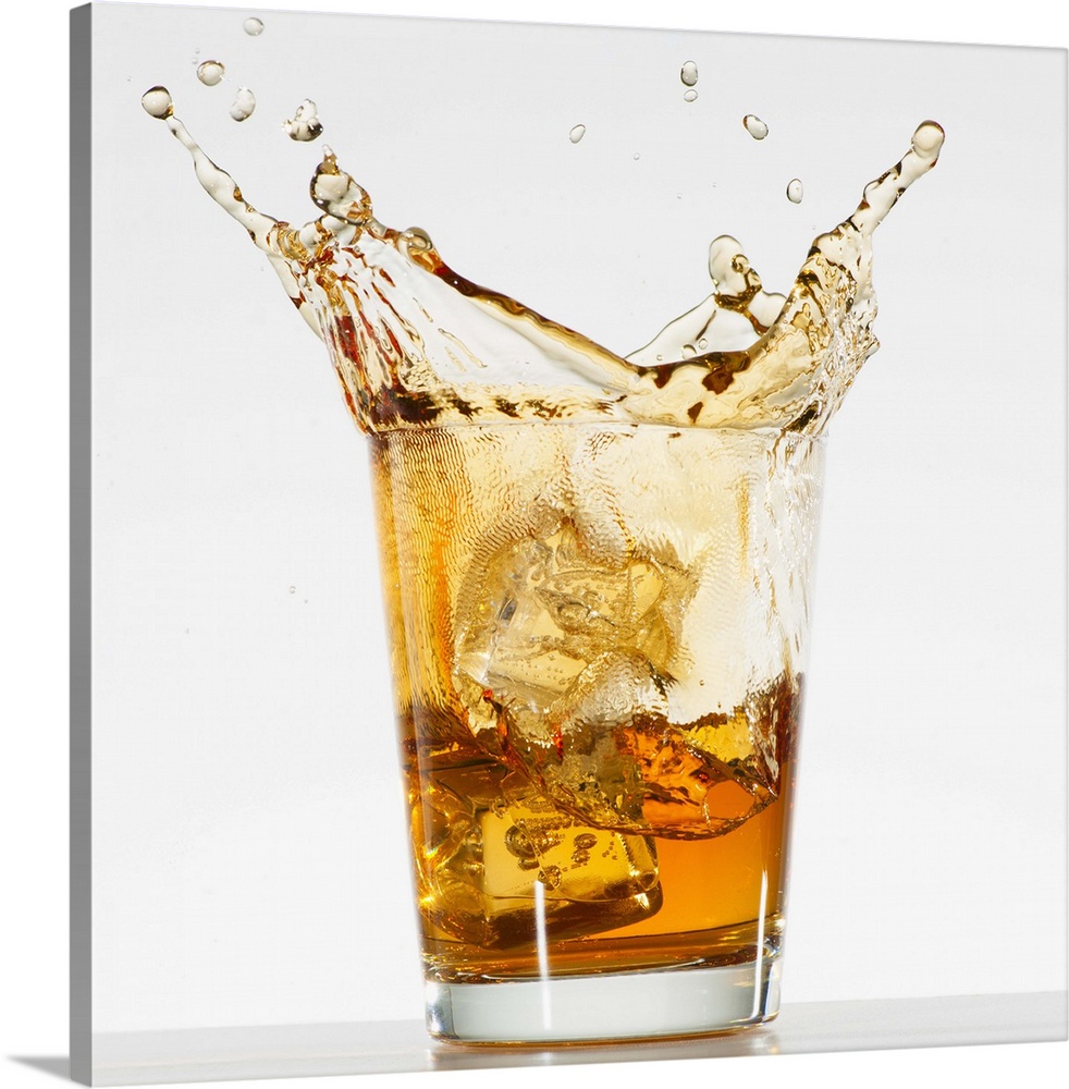 Studio shot of ice cubes splashing into glass of whiskey