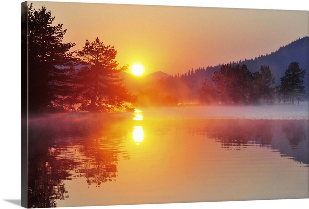Sunrise at mountain lake with island of pine trees.