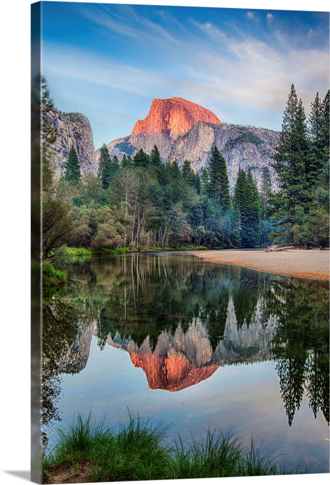 Half Dome in Yosemite National Park is reflected in the water of the Merced River at sunset.