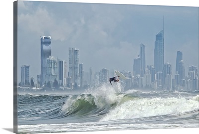 Surfer at burleigh heads with skyline of Surfers Paradise in background.