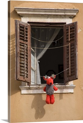Teddy bear hung out to dry on laundry line in window in Zadar, Croatia