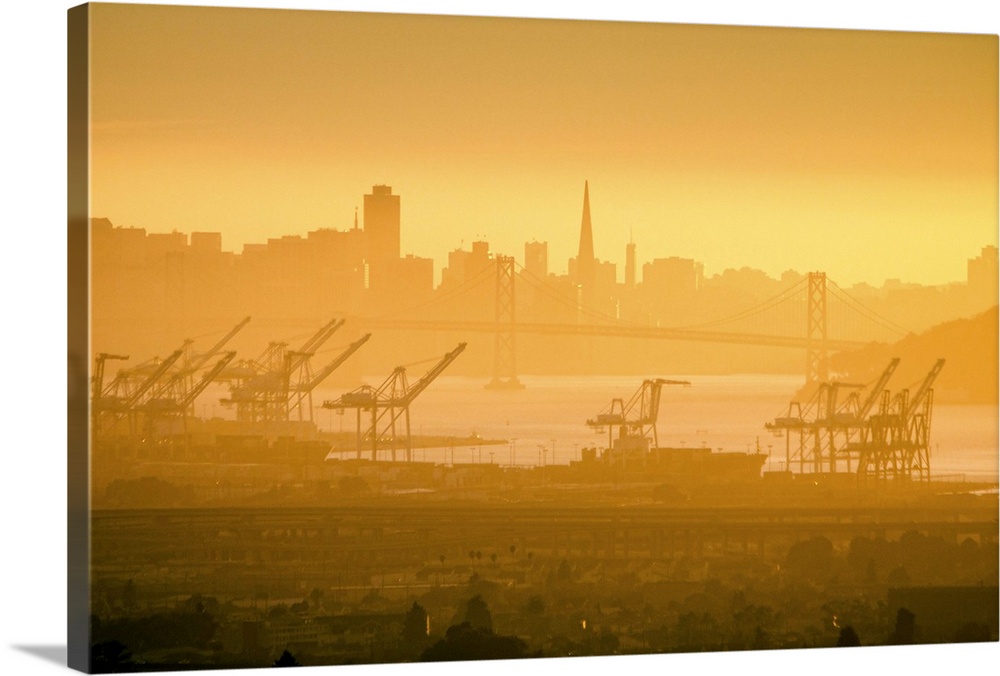 The San Francisco skyline from the Oakland Hills. The Bay Bridge and container cranes in the Port of Oakland are seen in t...