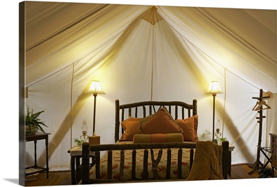 Tent interior with bed and lamps.