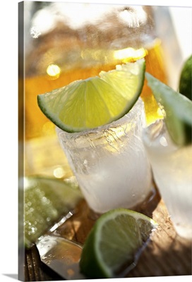 Tequila in shot glasses made of ice, with lime