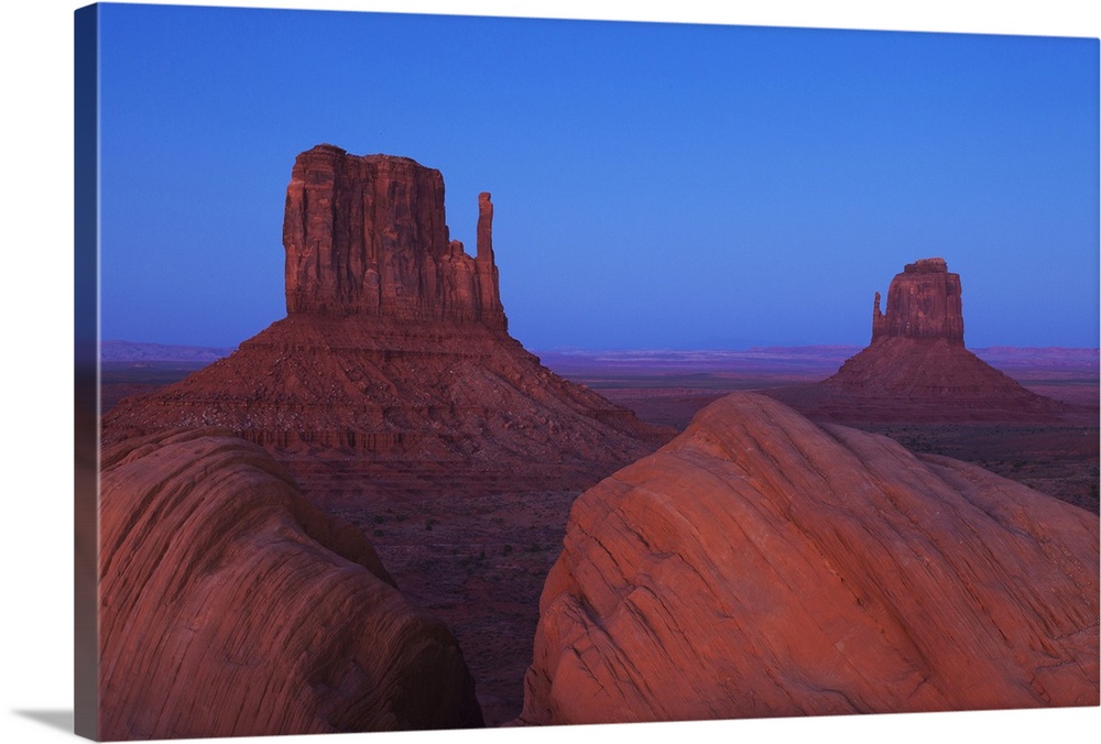 Monument Valley at dusk, with view of the West Mitten, the East Mitten and some foreground rock formations.  Monument Vall...