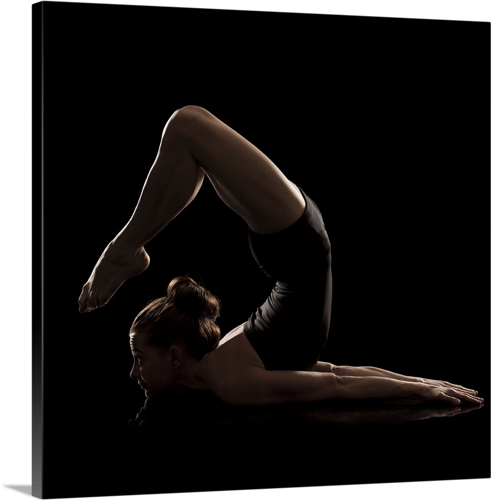 Studio shot of young woman practicing yoga.  The scorpion pose, vrshikasana