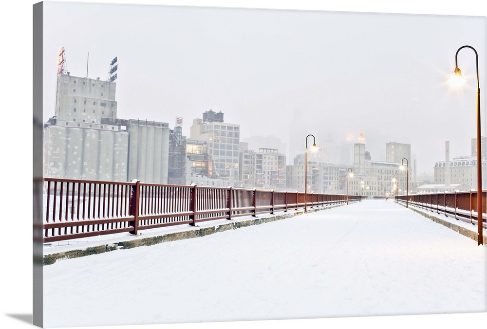 The Stone Arch Bridge in Minneapolis Minnesota during winter with snow on it.