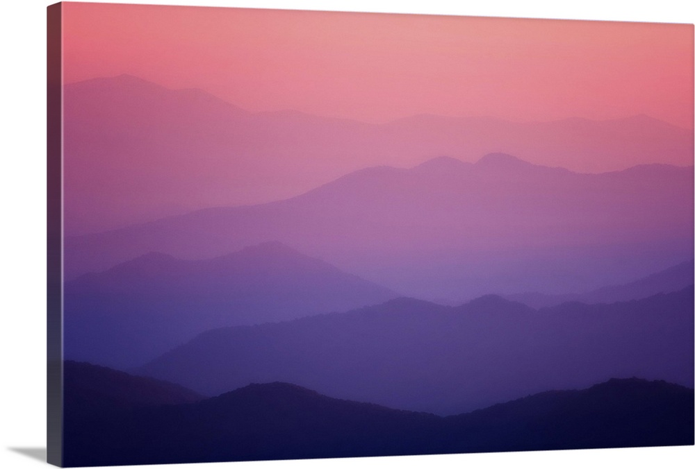 Layers of the smoky mountains reach into the distance as the sky turns pink and purple in the sunset.