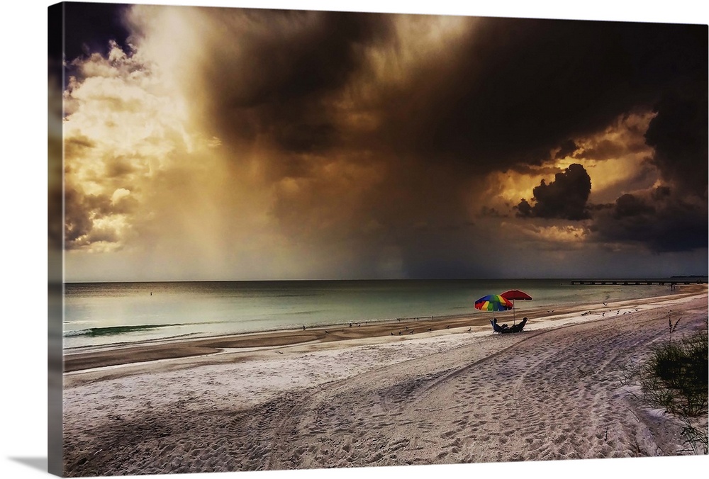 Tourists sit under sun shades on the beach as a storm approaches. Gulf Coast, Florida, USA.