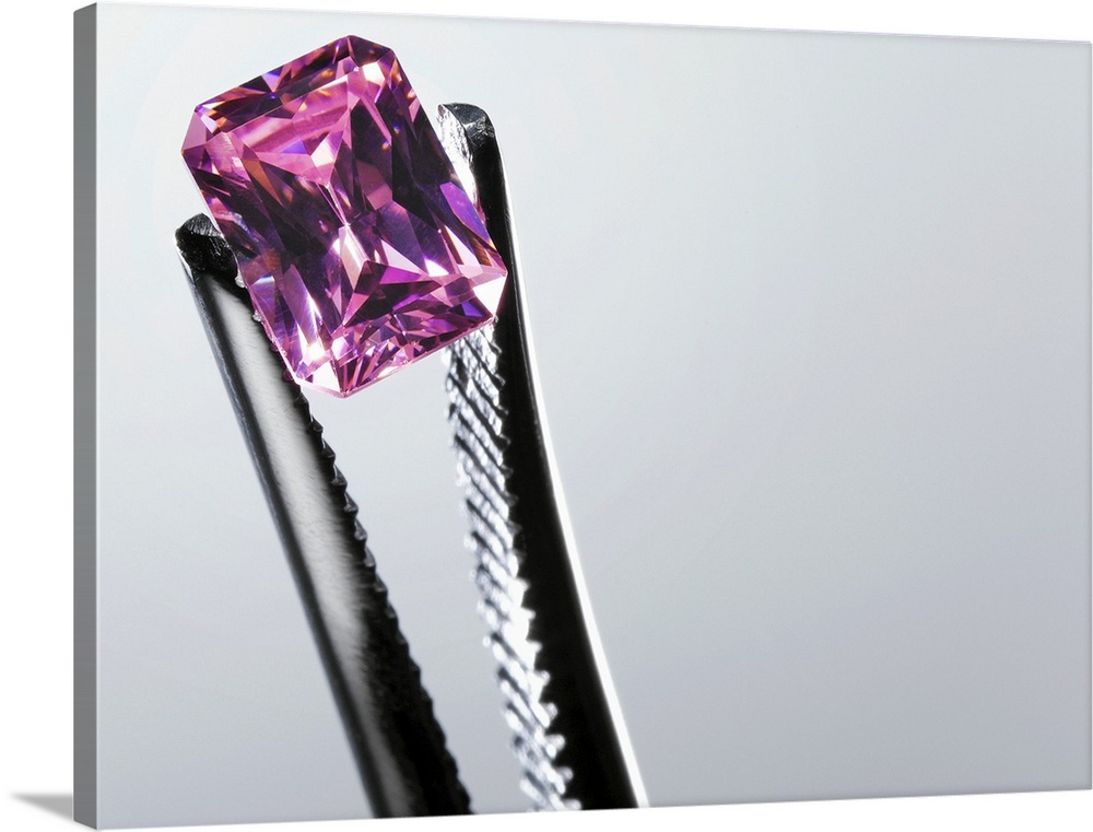 Tweezers holding small purple gem, close-up