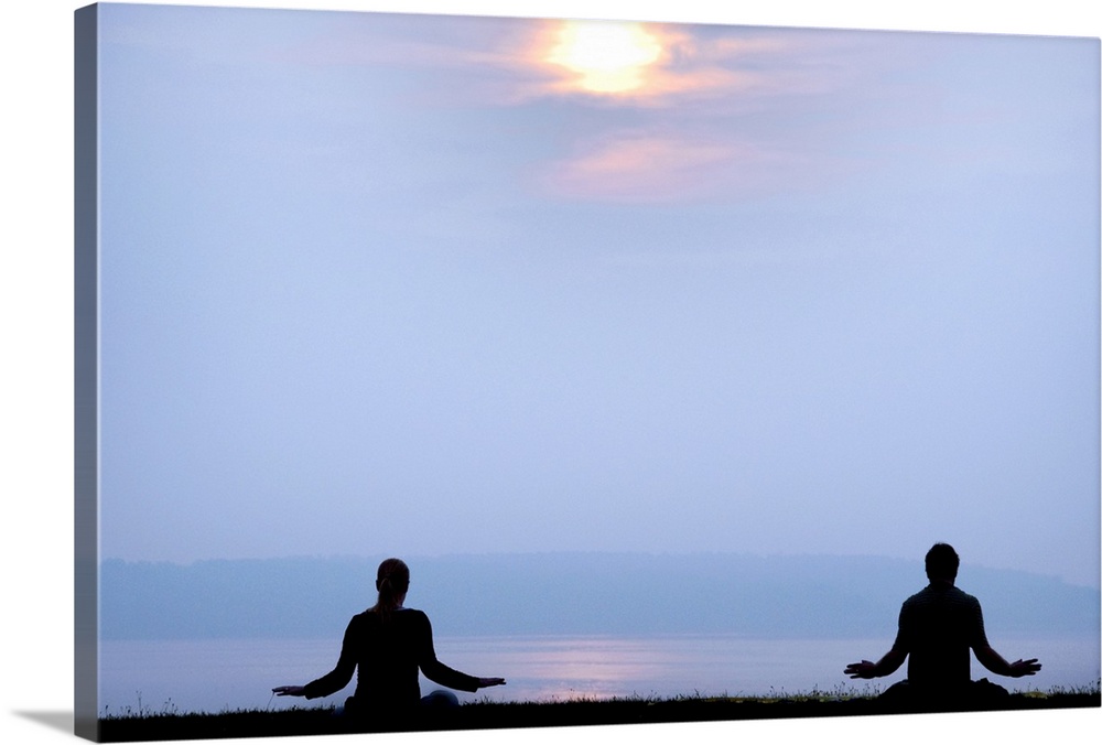 Two followers of the Falun Gong spiritual practice meditate at sunrise over the Atlantic ocean.