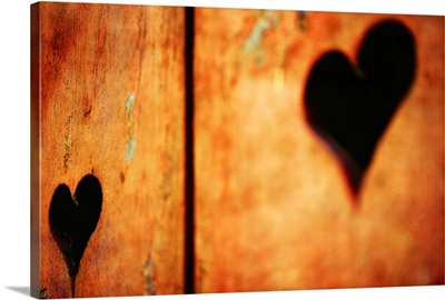 Two hearts carved on red wood shutters.