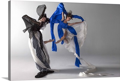 Two women jumping draped in silk