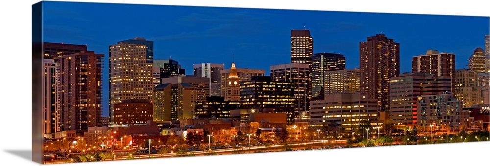 Panoramic photograph of lit up skyline under a clear sky.