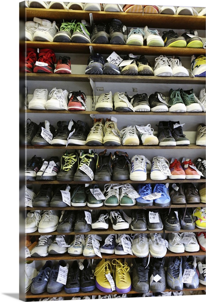 Various types of second hand trainers and casual footwear arranged on shelves.