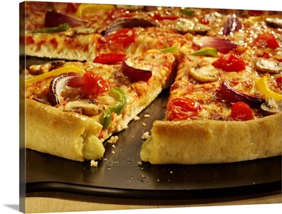 Vegetable pizza sliced on black pan on wood