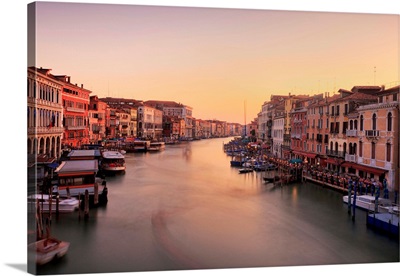 Venetian canal side palaces around Rialto Bridge glow in last of evening light.