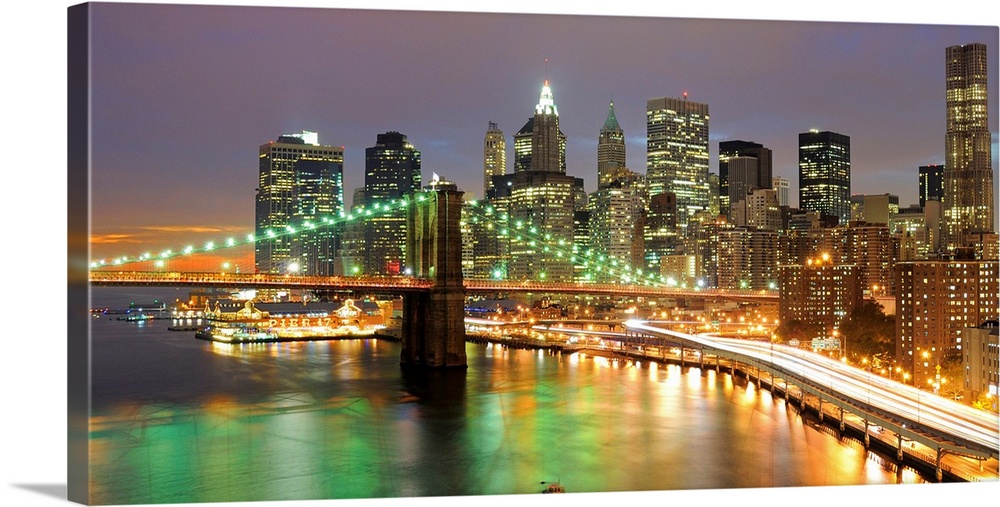 Oversized, horizontal photograph of bright lights of the Brooklyn Bridge and New York City, at night.
