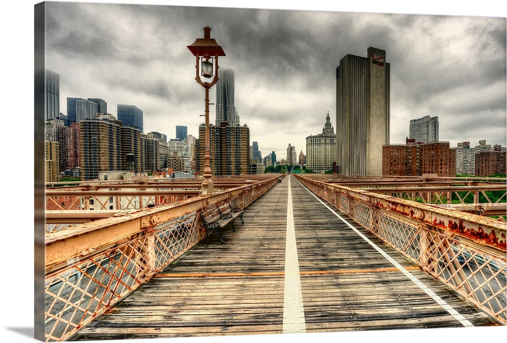 The towering skyscrapers of New York City against a dark, cloudy sky, as seen from a weathered bridge with rusted railings.
