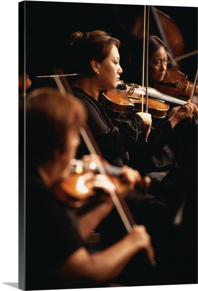 Violin section performing in orchestra (focus on woman)