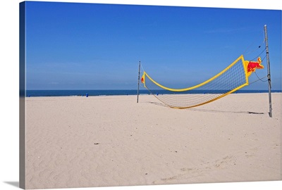 Volleyball net on beach with blue sky.
