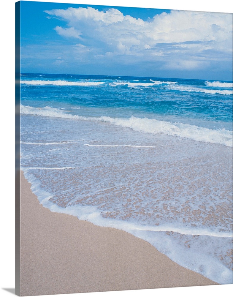 Photograph of small waves lapping on the white sandy beach.