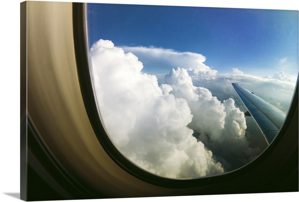 White fluffy clouds looking through airplane window.