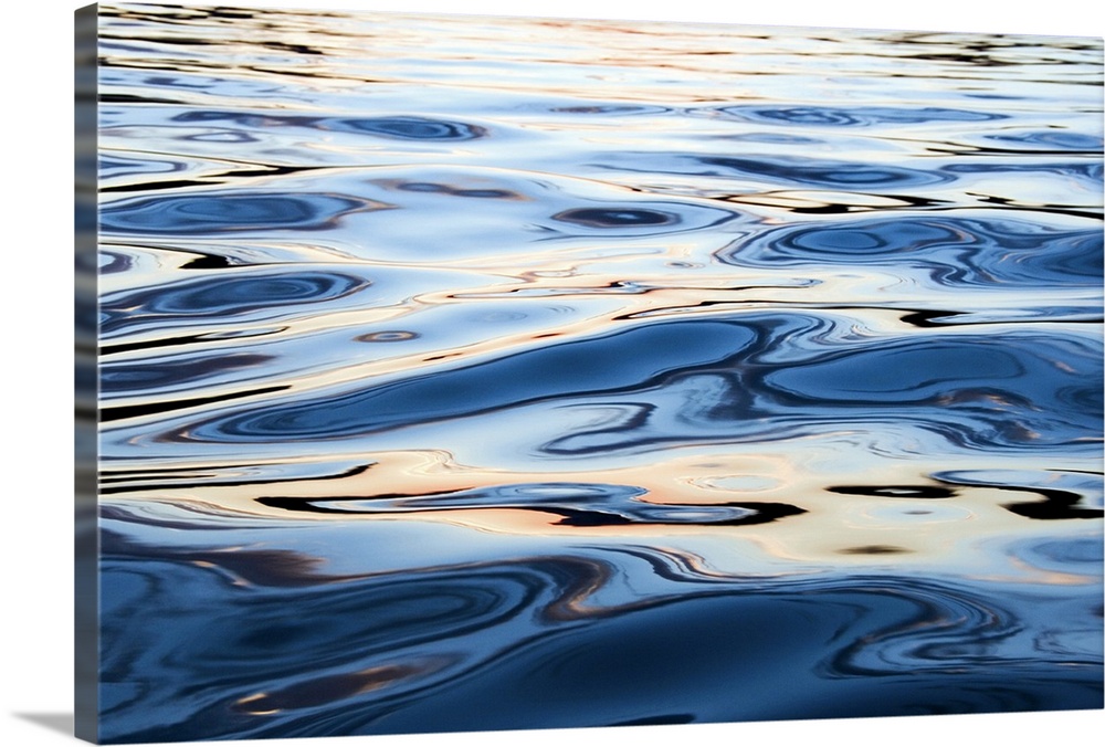 This is a close up nature photograph of the rippling surface of a body of water reflecting sunlight on its undulating surf...