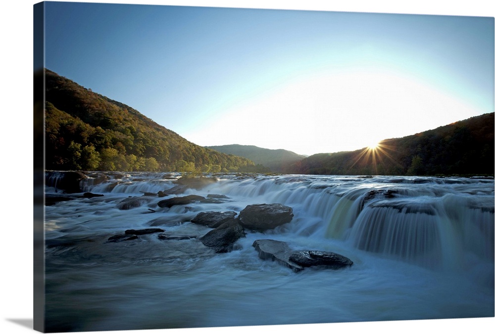 Wide waterfall seen in evening light with blurry water.