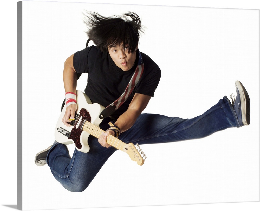 an asian teenage male in jeans and a black shirt jumps up wildly with his electirc guitar