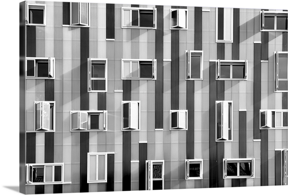 Black and white photograph of windows on the side of a building that are scattered about in no particular pattern.